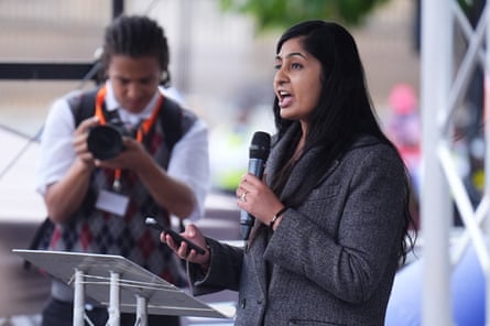 Sultana talks into a mic while wearing a big grey coat.