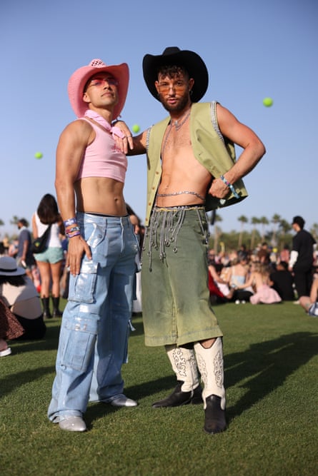 a person in a pink crop top and pink cowboy hat and loose blue jeans with cargo pockets next to a person in a green vest and green long shorts with black and while cowboy boots