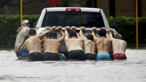 People push a stalled pickup to through a flooded street in Houston