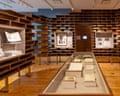 The Schomburg's centennial exhibit features curved wooden shelving walls, display cases with books, and framed items
