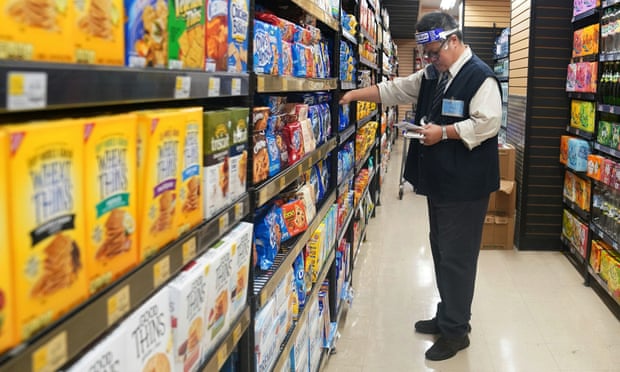A worker wearing a face shield checks products at a grocery store in New York, New York.