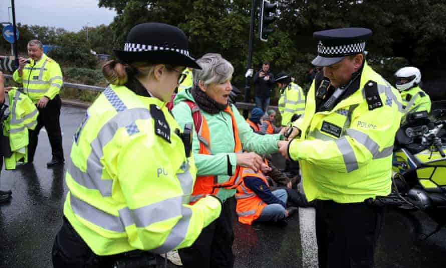 Police officers with an Insulate Britain activist at a motorway junction near Heathrow airport in London