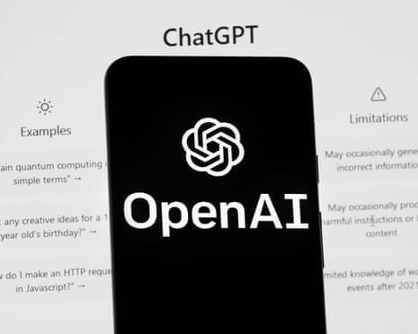 The OpenAI logo is seen on a mobile phone in front of a computer screen displaying the ChatGPT home screen