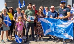 The first minister of Scotland, Humza Yousaf, holds a Yes sign with SNP activists in Glasgow
