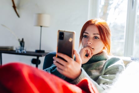 Young woman lying on a couch using her phone