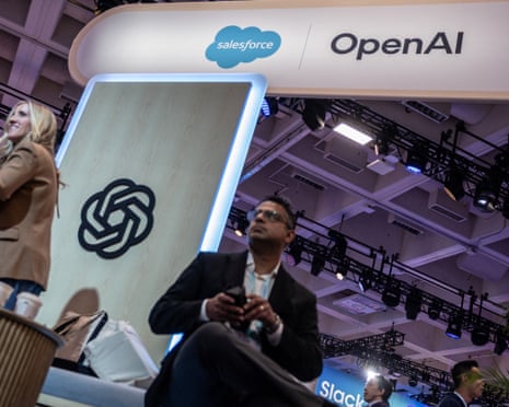 A man stands below a large Salesforce OpenAI sign at a technology conference booth