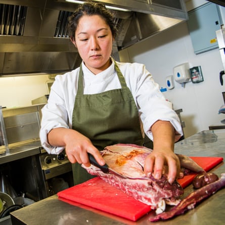 Nina Matsunaga in the kitchen slicing a joint of meat