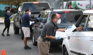 City employees hand out unemployment applications to people in their vehicles in front of the John F Kennedy library in Hialeah, Florida, on 8 April.