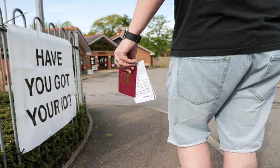 A voter brings his passport to the polling station in the 2018 local election in Woking
