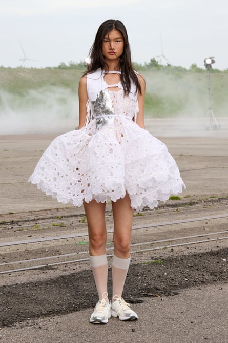 A model wearing a short white Celile Bahnsen dress and long socks, stood outdoors