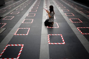 A woman kneels inside a social distancing marker to offer prayers to Ganesh in Bangkok