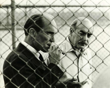 Robert Duvall, left, with Michael V Gazzo in The Godfather Part II standing behind a wire fence.