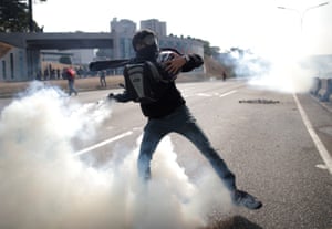 An opposition demonstrator throws back a tear gas canister