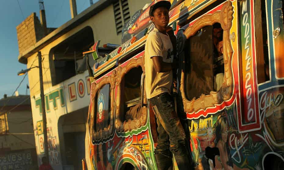 A teenager clings to a bus during 2010 Day of the Dead celebrations in Port-au-Prince, Haiti