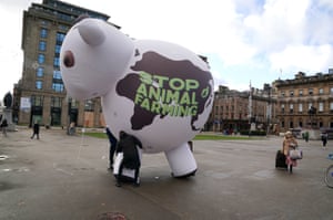 Climate activists from The Plant Based Treaty carry an inflatable cow through George Square in Glasgow
