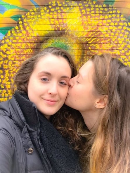 Amanda Smith besa a su pareja Karen en la mejilla frente a un mural floral amarillo