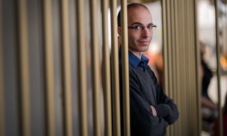 Yuval Noah Harari, wearing glasses and smiling slightly, crosses his arms