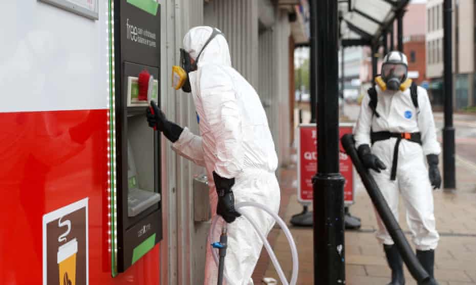 A man in PPE cleans an ATM machine