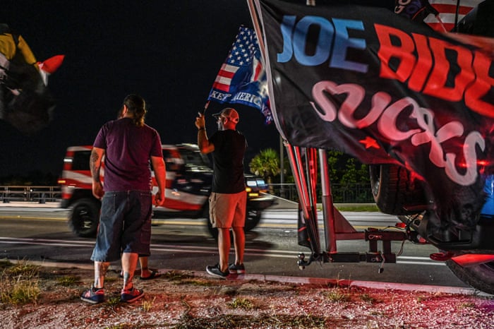 Some supporters stood outside the former US President’s residence holding flags while media watched on.