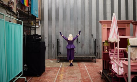 Katherine Kingsley raises her arms behind the backstage safety curtain