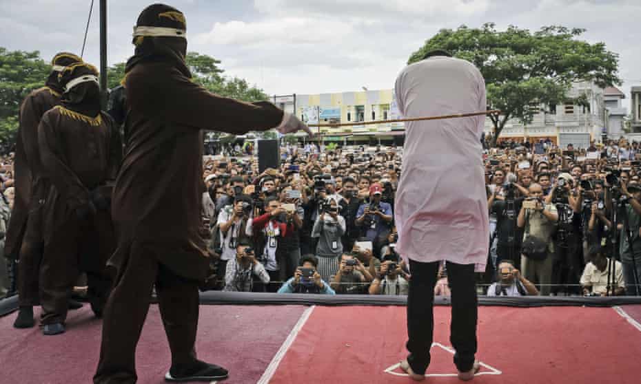 A sharia law official canes a man convicted of gay sex during a public caning in Banda Aceh, in May last year.