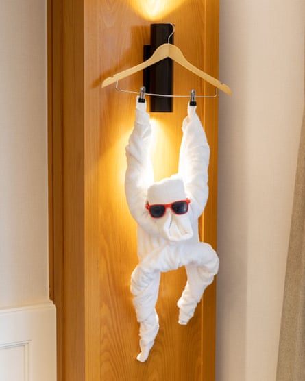 A towel made into a monkey with sunglasses hanging from a door
