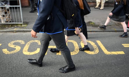 school sign on road with pupils walking past