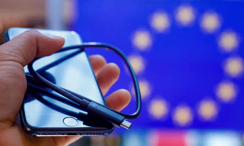 An iPhone with a USB-C cable in front of a EU flag.