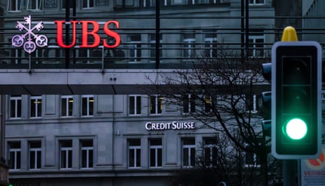 The logos of the Swiss banks Credit Suisse and UBS are displayed on different buildings behind traffic lights in Zurich, Switzerland,