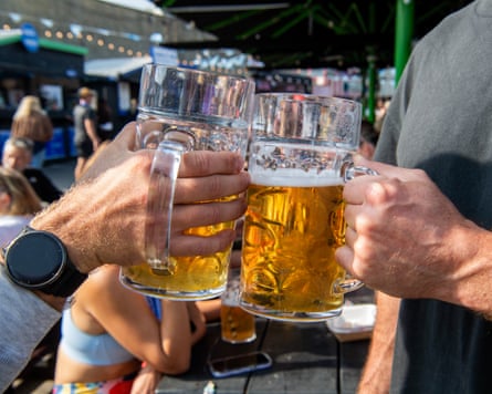 Close-up of two hands clinking large beer glasses
