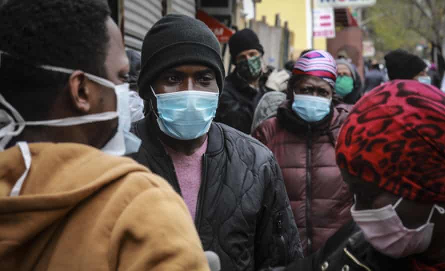 People wait for a distribution of masks and food from the Rev. Al Sharpton in the Harlem neighborhood of New York.