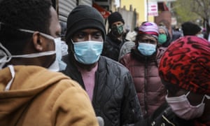 People wait for a distribution of masks and food in Harlem, New York. Many black Americans are already feeling the economic pinch of the coronavirus.