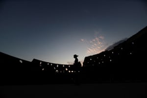 A person in silhouette strolls inside the Colosseum during a night tour