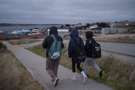 Three schoolchildren with backpacks walk along a path