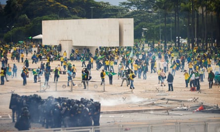 Des manifestants portant des drapeaux brésiliens vandalisent une zone devant le Congrès national