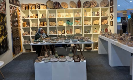 A woman selling ceramics waits for her first customer of the day at one of the artisanal stalls in the government expo tent in the Green Zone