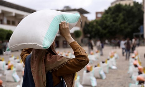 A worker carries a sack of wheat flour during the distribution of food aid by the local charity, Mona Relief, in Sanaa, Yemen.