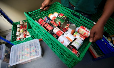 Box of canned food being held by volunteer at foodbank