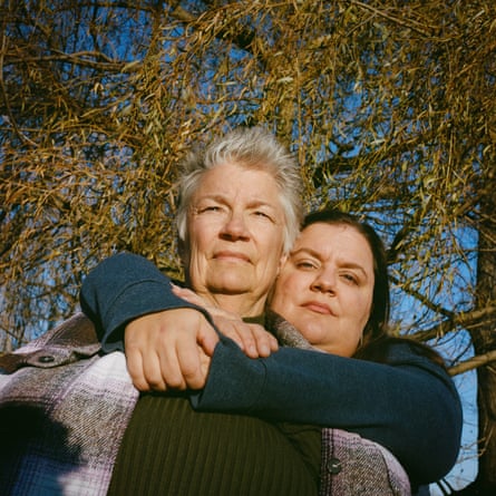 Two women, the younger one hugging the older one from the back, beneath a tree.