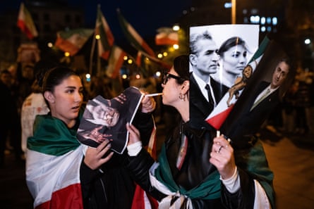Women draped in Iranian flags holding poster of the shah of Iran and burning a poster