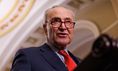 a man in a blue suit and red tie speaks from behind a lectern