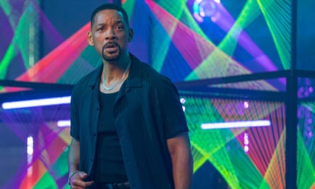 film still of a man in a black shirt in front of neon lights