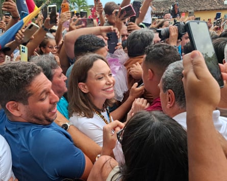 Machado surrounded by a crowd of supporters in the street, many of then taking photos on their phones