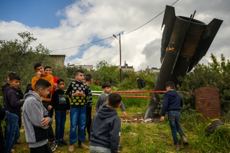 फ़िलिस्तीनी नागरिक ज़मीन में दबी एक ईरानी मिसाइल के पास इकट्ठा होते हैं