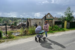 Moshchun, Ukraine: a woman pushes a pram near houses that were destroyed by Russian shelling in Kyiv