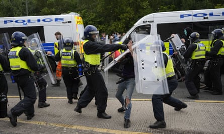 Riot police with shields take on a man in jeans
