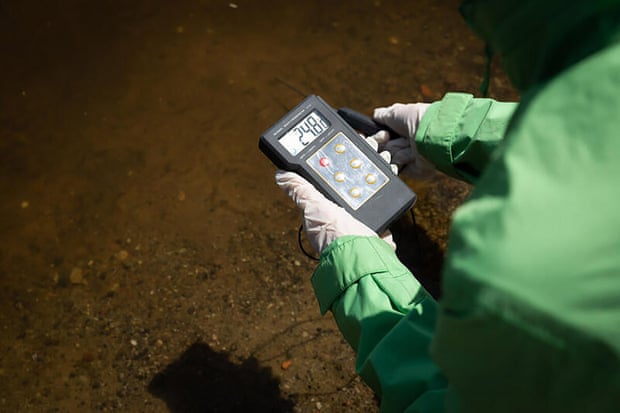 Alguém segura um monitor eletrônico enquanto testa os níveis de algas em um lago