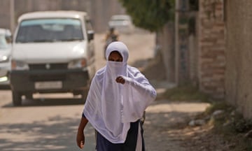 A schoolgirl covers her face with a scarf on a hot  afternoon