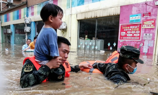 Rescuers evacuating a child from a flooded area following heavy rains in Suizhou, China.