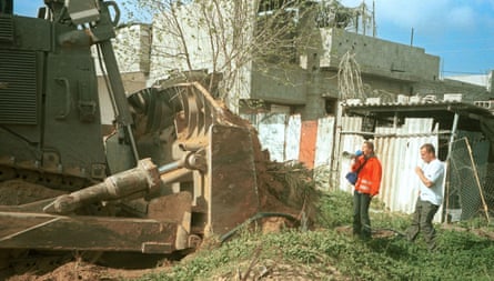 a woman speaks into a microphone in the direction of a bulldozer